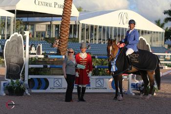 Alvaro ‘Doda’ Miranda, mounted on AD Uutje, is presented with a ,000 bonus from Jennifer Ward on behalf of SSG Gloves for wearing SSG ‘Digitals’ on his way to victory in the 5,000 WEF Challenge Cup Round VII at the 2014 FTI Consulting Winter Equestrian Festival in Wellington, FL. Photo by Sportfot