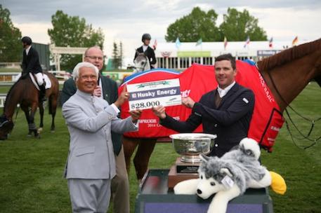 Conor Swail raises his winning check with Asim Ghosh, President & CEO of Husky Energy. Photos © Spruce Meadows Media Services.