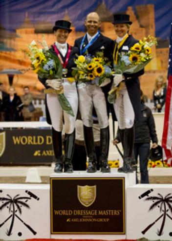 Tinne Vilhelmsson Silfven, Steffen Peters and Tina Konyot stand on the podium before a back drop of a Southern French scene during the awards presentation. (Photo By: Susan J. Stickle)