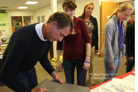 Carl Hester signs back of painting 