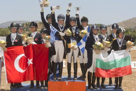 A happy moment on the podium during the presentation of the Junior Team medals at the FEI Balkan Dressage Championshps 2016 in Athens (GRE) last weekend. (L to R): Bulgaria’s bronze medallists Stephanie Neseva, Irina Nikolva, Mirela Raikova and Katerina Tvetanova; the newly-crowned Greek champions Elisavet Maika, Lavinia Macropoulou, Eleni Retsou and Theodora Livanos: and Turkey’s silver medallists Dila Akbackaloglu, Iren Kaplan, Derin Lara Ekici and Lara Tumay. (FEI/Alexis Valilopoulos)