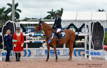 Canada’s Vanessa Mannix, riding Valerie F.S., is presented with a ,000 bonus from Jennifer Ward on behalf of SSG Gloves for wearing SSG ‘Digitals’ on her way to victory in the 5,000 High Amateur-Owner Jumper Classic at the 2015 Winter Equestrian Festival in Wellington, FL.  Photo by Starting Gate Communications
